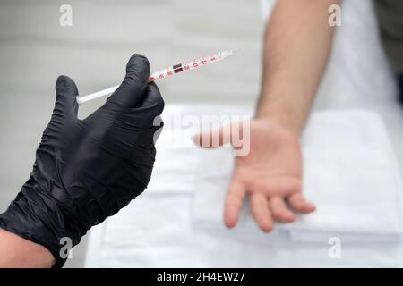 il medico fa un colpo di tossina botulinica nelle mani di un palmo maschio contro sudorazione eccessiva, trattamento di iperidrosi Foto Stock