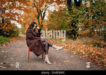 Giovane bella donna con vecchia poltrona sulla corsia di campagna in autunno Foto Stock