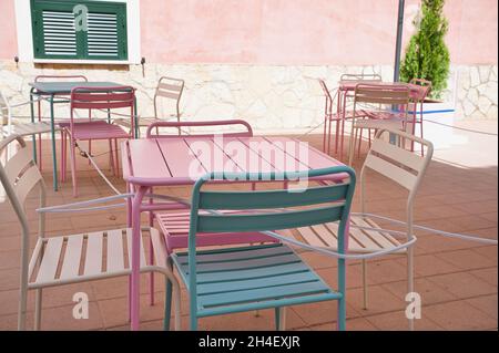 Sedie e tavoli color pastello all'aperto, un ristorante chiuso in estate a Maiorca Foto Stock