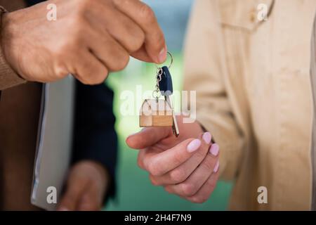 vista ritagliata del realtor che dà la chiave alla donna all'interno della nuova casa Foto Stock