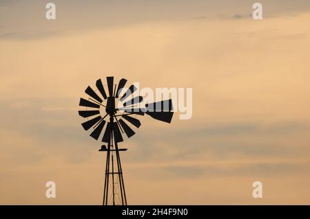 La silhouette di un vecchio mulino a vento in una fattoria in un tramonto dorato. Barker, Colonia, Uruguay Foto Stock