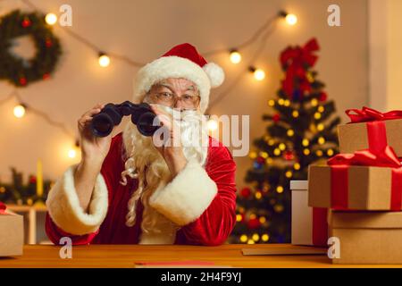 Natale del vecchio padre con binocoli che spionano su chi è stato naughty o piacevole quest'anno Foto Stock