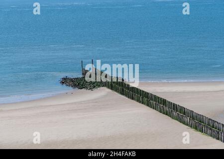 Vista ad angolo alto di due file diagonali parallele di frangiflutti di legno sulla spiaggia di Westkapelle, i Paesi Bassi durante la bassa marea con solo la fine re Foto Stock