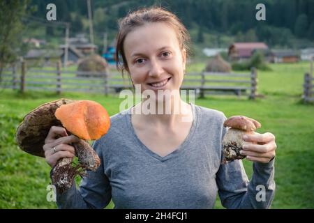 Primo piano ritratto donna con emozioni positive e funghi bianchi in mano Foto Stock