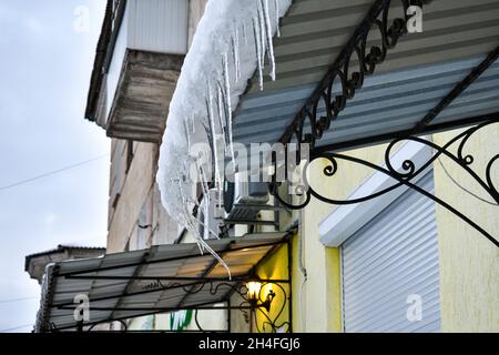 Sul tetto del balcone si alzeranno ghiacciate trasparenti dalla neve gelata che si scioglie. Foto Stock