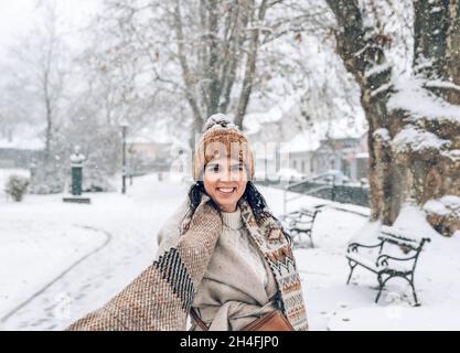 Ritratto di una bella giovane donna in eleganti abiti invernali in piedi nel parco nevoso. Foto Stock