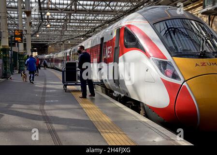 Un membro del personale ferroviario LNER carica le forniture di catering in un treno Azuma Hitachi classe 801 alla stazione ferroviaria di Edinburgh Waverley, Scozia, settembre 2021 Foto Stock