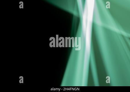 Sfondo astratto, raggi verdi al neon verticali e diagonali su sfondo nero. Fornisce spazio per il testo. Foto Stock