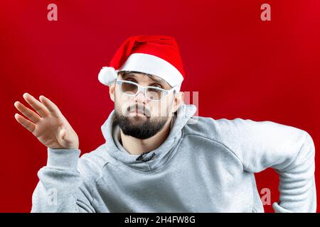 Un uomo vestito di abiti Babbo Natale mise la sua mano a lato e pensa Foto Stock