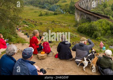 GLENFINNAN, SCOZIA - 3 SETTEMBRE 2021: Folle di persone si riuniscono per guardare il tradizionale treno a vapore Jacobite che attraversa il famoso viadotto a Glenfinn Foto Stock