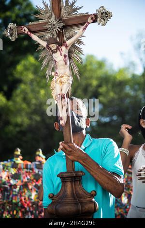 Salvador, Bahia, Brasile - 01 gennaio 2021: Uomo che indossa una maschera facciale e porta una croce con l'immagine di Gesù Cristo nella chiesa di Senhor do Bonfim Foto Stock