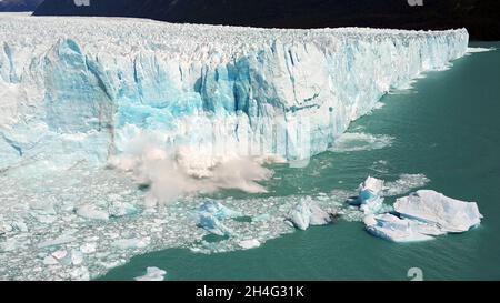 vista con droni di un grande pezzo di ghiaccio ghiacciato che si rompe a causa della fusione del ghiaccio e che cade in mare, a causa del cambiamento climatico, in una giornata di sole. Foto Stock