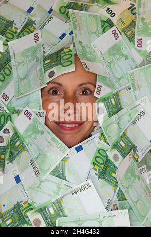 Concetto di vita piena di soldi, il volto sorridente di una donna circondato da 100 euro bollette Foto Stock