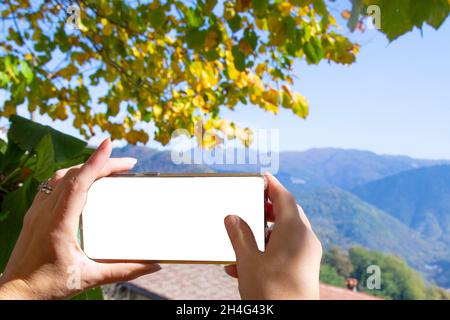 le mani femminili scattano le immagini con il telefono il paesaggio autunnale bello nelle montagne Foto Stock