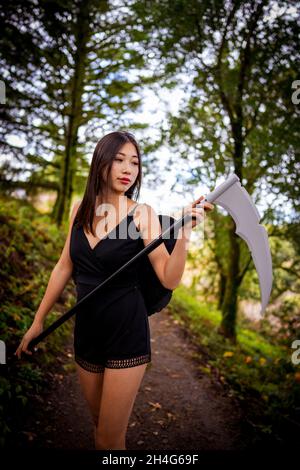 Giovane donna che indossa un vestito Cosplay Grim Reaper in The Woods Foto Stock