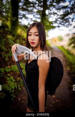 Giovane donna che indossa un vestito Cosplay Grim Reaper in The Woods Foto Stock