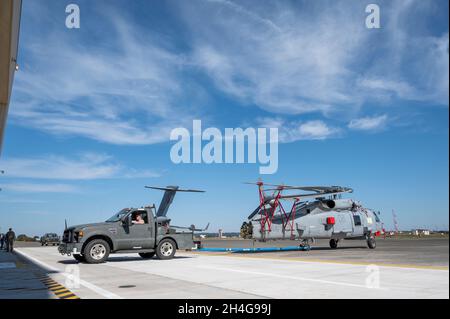 Royal Australian Navy Leading Seaman Steven Marsetti, 816 Squadron Flight 4, tecnico di aerei, trasporta un MH-60R Seahawk in un hangar, 30 ottobre 2021, presso la Yokota Air base, Giappone. Il modello MH-60R fornisce unità DI superficie RAN con capacità di sorveglianza anti-sottomarina e anti-superficie. (STATI UNITI Air Force foto di staff Sgt. Juan Torres) Foto Stock