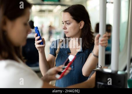 Donna che usa il telefono nei trasporti pubblici Foto Stock