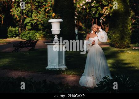 sposa in giardino, mattina e sposa, spese di sposa, sposa del mattino, abito bianco, indossare gli orecchini Foto Stock