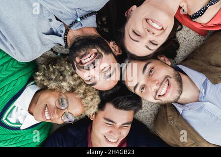 Giovani persone multietniche che si trovano in cerchio mentre si diverte all'aperto - concentrarsi sulla faccia destra dell'uomo Foto Stock