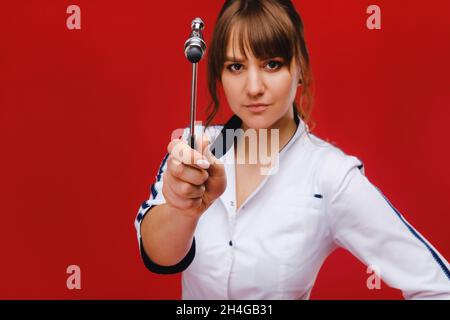 Esame neurologico. Il neurologo che esamina i riflessi su una paziente femminile utilizzando un martello. Diagnostica, assistenza sanitaria, assistenza medica. Foto Stock