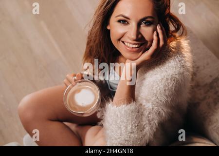 Ragazza rilassata a casa bere coffee.Inner peace.The ragazza è seduta comodamente sul divano e bere caffè. Foto Stock