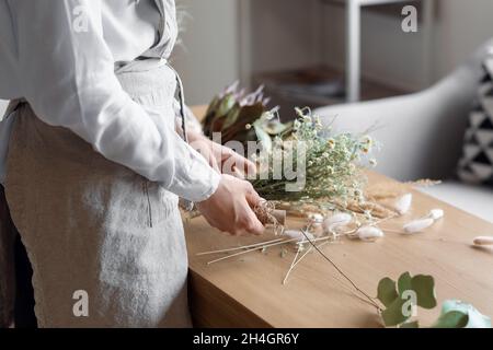 Fiorista femminile che fa bouquet con bei fiori secchi a tavola Foto Stock