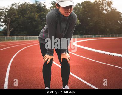 Una donna stanca che si riposa dopo aver corso duramente sulla pista dello stadio. Concetto di stile di vita sano di allenamento. Foto Stock