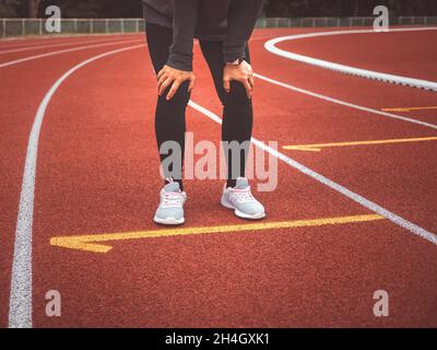 Una donna stanca che si riposa dopo aver corso duramente sulla pista dello stadio. Concetto di stile di vita sano di allenamento. Foto Stock