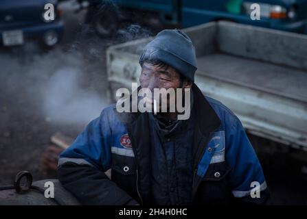 Un minatore si riposa mentre attende di iniziare a caricare carbone grezzo per essere trasportato alla capitale da una miniera informale a Nalaikh, un povero quartiere urbano 36 km Foto Stock