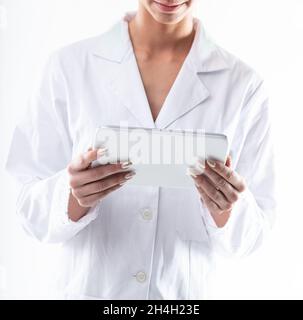 Donna in camice da laboratorio bianco che tiene un tablet-pc in una vista ravvicinata ritagliata sulle mani adatto per l'uso in temi medici Foto Stock