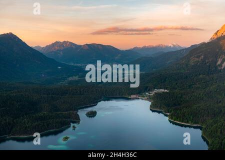 Vista sul lago Eibsee al tramonto, alpenglow, dietro Bishop e Krottenkopf, Wetterstein montagna, vicino Grainau, alta Baviera, Baviera, Germania Foto Stock
