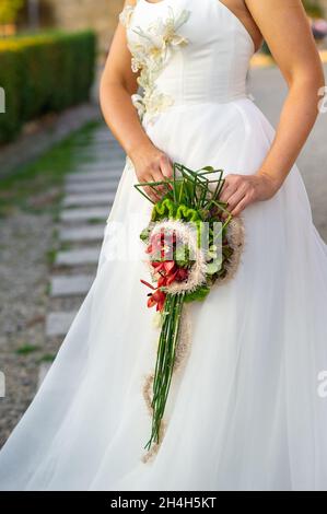 un bouquet di nozze allungato inusuale nelle mani della sposa. Foto Stock