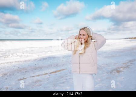 Donna felice di mezza età che indossa bianco clotheswalk da solo lungo la spiaggia di mare d'inverno o oceano e respirare con aria fresca fredda Foto Stock