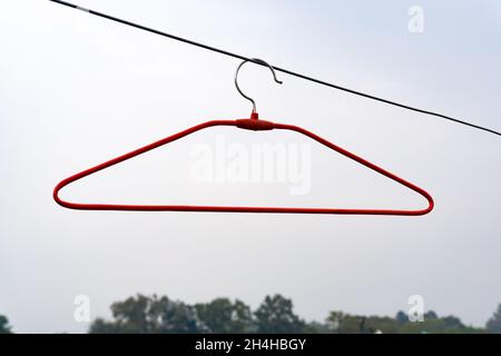 Un appendiabiti rosso vuoto all'esterno con gli alberi sullo sfondo. Foto Stock