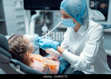 Il dentista femminile tratta i denti della piccola ragazza paziente all'ufficio dentale. Odontoiatria concetto Foto Stock