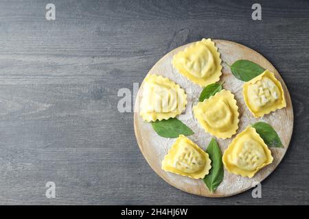 Tavola con ravioli crudi su sfondo di legno scuro Foto Stock