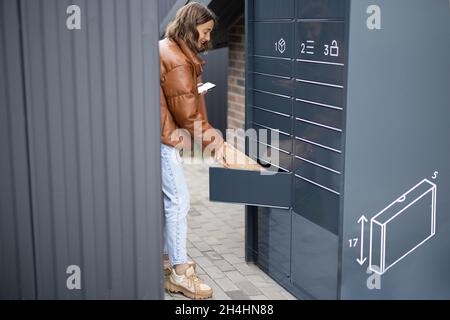 Donna che mette il pacco alla cella del terminale del posto Foto Stock