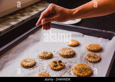 Donna spolverata spezie scones pronto per andare in forno. Primo piano Foto Stock
