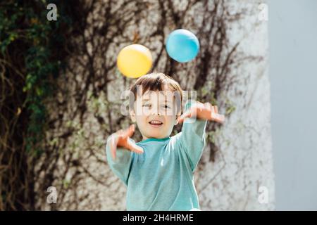 Bambino gettando sfere di plastica colorate con le mani. Foto Stock