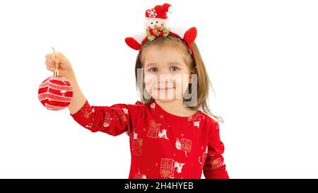 Un bambino che tiene una palla di Natale e sorridente. Ragazza bionda con baubles di Natale isolato su sfondo bianco. Bella faccia di un bambino con un positivo Foto Stock