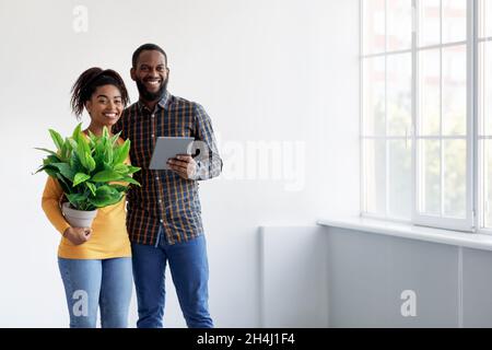 Allegro millenario coppia afroamericana che si muove in nuova casa e interni di pianificazione Foto Stock