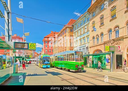 Graz - 2020 giugno, Austria: Vista di una fermata del tram con moderni tram colorati e splendidi edifici antichi in stile architettonico tradizionale Foto Stock