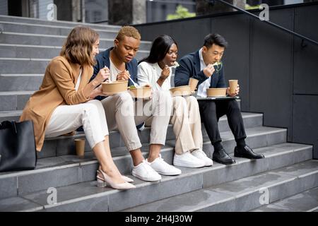 Il team di lavoro parla, mangia e beve sulle scale Foto Stock