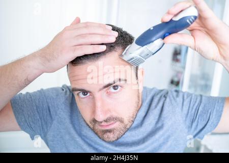 Uomo auto taglio capelli da solo guardando lo specchio Foto stock
