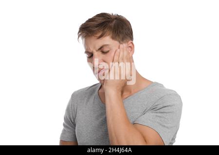 Infelice triste millenario uomo caucasico preme mano a guancia e soffre di mal di denti Foto Stock