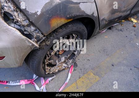 Ruota rotta e bruciata del primo piano dell'auto. Sommossa, protesta civile, hooliganismo, criminale in città. Foto Stock