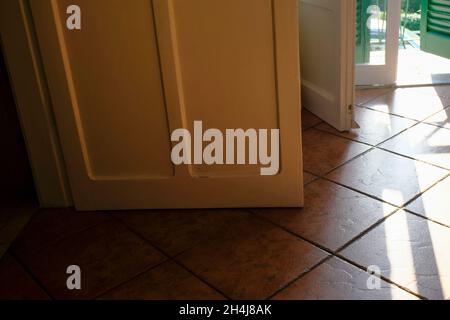 porta bianca in legno da oltre, pavimento piastrellato attraverso le porte aperte al balcone. Interni domestici. Camera Foto Stock