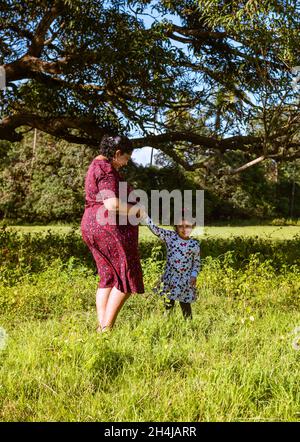 Famiglia indiana di madre e toddler in un giardino e in previsione di un secondo bambino Foto Stock