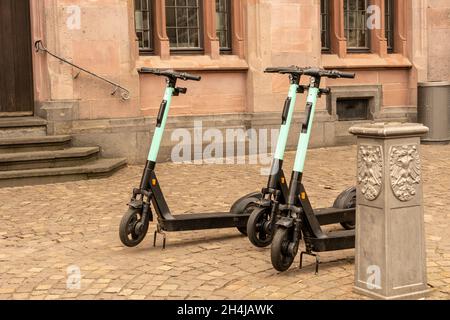 Dopo l'uso, tre e-scooters sono parcheggiati di fronte ad un edificio storico nel centro della città Foto Stock